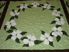 a green and white quilt with flowers on it