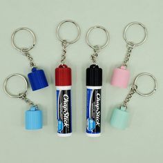 four key chains with different colored batteries attached to them, and one has a lighter on it