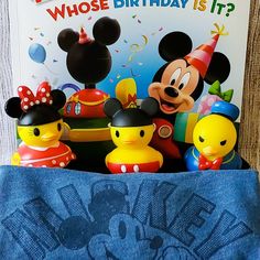 mickey mouse and other toys are in the back pocket of a blue bag that says who's birthday is it?