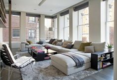 a living room filled with lots of furniture next to large windows and floor to ceiling windows