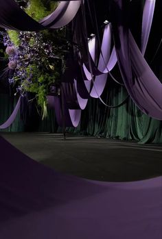 an image of a stage setting with purple draping and flowers on the ceiling