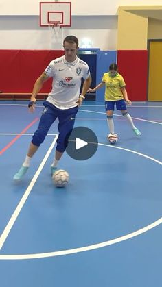 two men are playing soccer on an indoor court