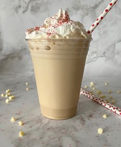 there is a drink with whipped cream and sprinkles on the table next to a candy cane