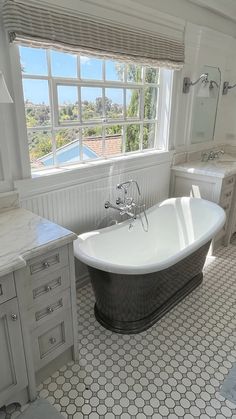 a bathroom with a claw foot bathtub next to a window