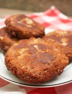 three patties on a white plate with red and white checkered table cloth in the background