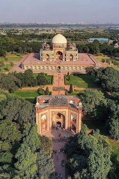 an aerial view of a large building in the middle of some trees and people walking around