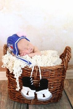 a baby sleeping in a basket wearing a hat and booties on top of it