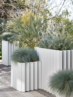 three tall white planters sitting on top of a wooden deck