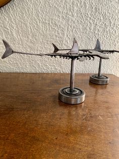 three metal shark sculptures sitting on top of a wooden table