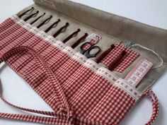 a red and white checkered apron with scissors, thread, and sewing needles in it