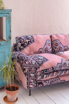 a pink couch sitting next to a potted plant