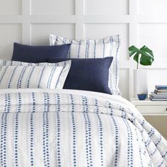 a bed with blue and white striped comforter in a bedroom next to a plant