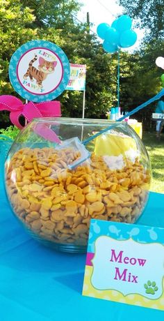 there is a bowl full of dog treats and a sign on the table that says meow mix