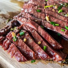 sliced up meat on a cutting board with green onions and seasoning sprinkles