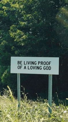 a sign that says be living proof of a loving god in front of some trees