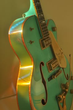 an old green guitar is on display in a museum case, with its light reflecting off the top