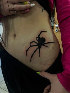 a woman's belly with a spider tattoo on her stomach and the bottom part of her abdomen