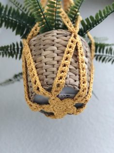 an ornament made out of woven material with green leaves on top, hanging from a tree branch