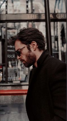 a man with long hair and beard walking down the street in front of a building