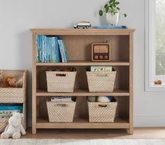 a bookshelf with baskets and stuffed animals on it next to a teddy bear