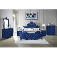 a blue bed sitting on top of a wooden floor next to a dresser and mirror