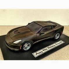 a cake shaped like a sports car on a black plate with the words happy new year written across it