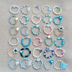 many different bracelets are arranged together on a cloth surface, one is blue and the other is white