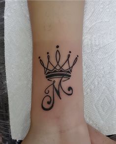 a black and white photo of a wrist tattoo with a crown on it's side