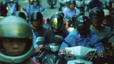 a group of people riding on the back of scooters down a busy street