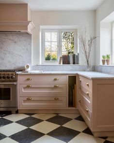 a kitchen with checkered flooring and pink cabinetry is pictured in this image