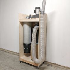 a wooden shelf with a vacuum and other items in it on top of concrete flooring