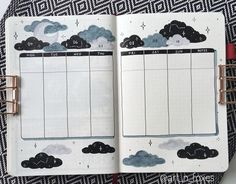 an open planner with black and white clouds on the page, next to a red pen