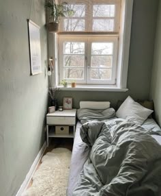 a bed sitting under a window next to a small table with a potted plant