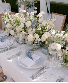 the table is set with white and blue flowers