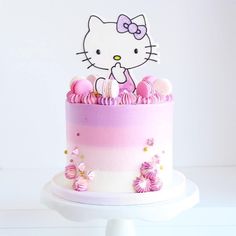 a hello kitty cake is decorated with pink and white icing on a pedestal stand