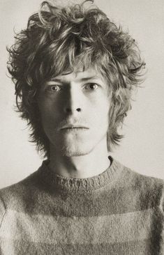 a black and white photo of a young man with curly hair looking at the camera