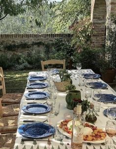 an outdoor table set with blue plates and glasses