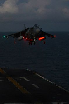 a fighter jet taking off from the flight deck of an aircraft carrier in the middle of the ocean