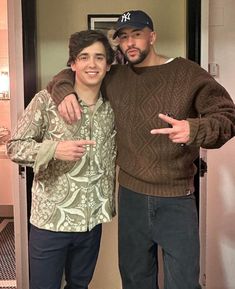 two men standing next to each other posing for a photo in front of a mirror