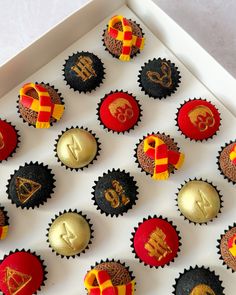 cupcakes decorated with harry potter symbols are in a white box on a table