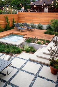 an outdoor hot tub in the middle of a patio with chairs and lights above it