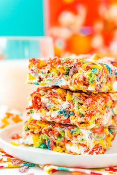 colorful cereal bars stacked on top of each other in front of a glass of milk