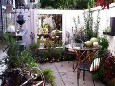 an outdoor patio with table and chairs surrounded by plants