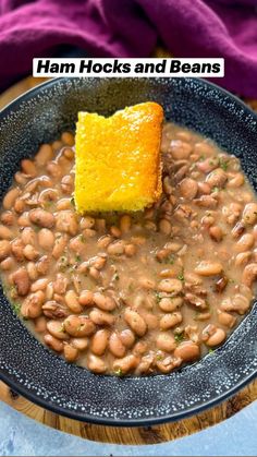 a black bowl filled with beans and a piece of bread