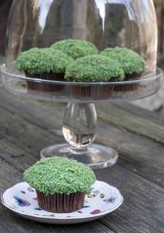 cupcakes covered in green frosting sitting on a plate next to a cake stand