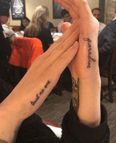 two people with matching tattoos holding each other's hands in front of their faces