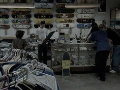 three people standing in front of a store filled with skateboards