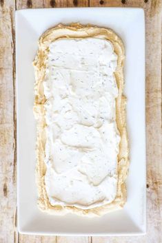 a square white plate topped with food on top of a wooden table