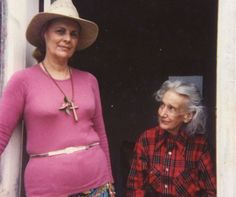 an older woman standing next to a younger woman in front of a door with her hand on her hip