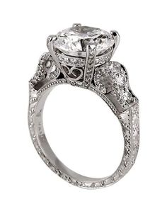 a diamond engagement ring with an intricate design on the band and center stone set in white gold